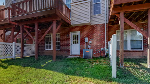 Back view of a house with a brick facade and raised wooden deck.