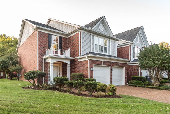 Front view of a two-story brick house with a white balcony and double garage.