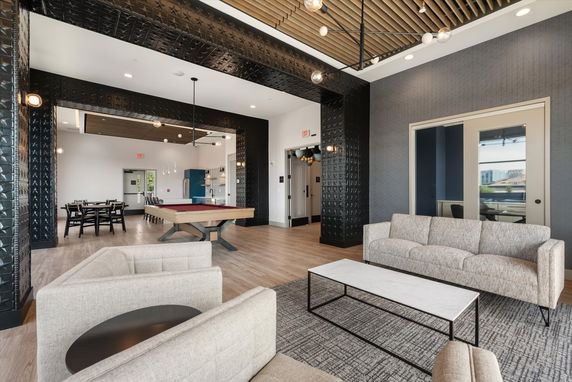 Interior view of a modern clubhouse with a pool table, seating area, and dining table.