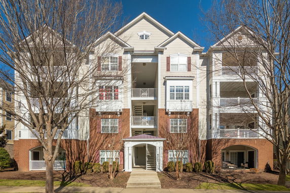 Front view of a multi-story residential building with balconies and brick facade.