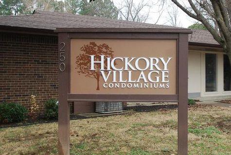 Front view of a condominium building with a sign reading 'Hickory Village Condominiums'.
