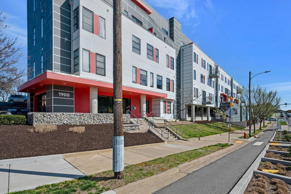 Front view of a modern multi-story building with red and gray facade.