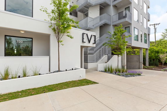 Front view of a modern multi-story building with outdoor stairs and large windows.