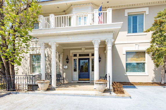 Front view of a house with a balcony and decorative columns.