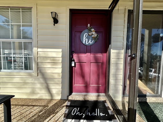 Front view of a house entrance with a red door and welcome mat.