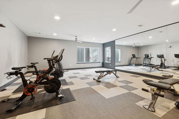Indoor gym area with exercise bikes, a bench, and a mirror wall.