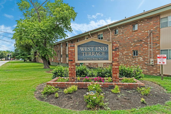Front view of a multi-story brick apartment building with a sign reading 'West End Terrace'.