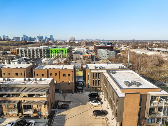 Aerial view of buildings with flat rooftops featuring air conditioning units and parking areas below.