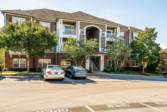 Front view of a multi-story residential building with a parking area in front.