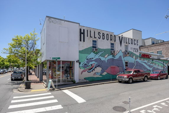 Front view of a building in Hillsboro Village with a colorful mural and street signs.