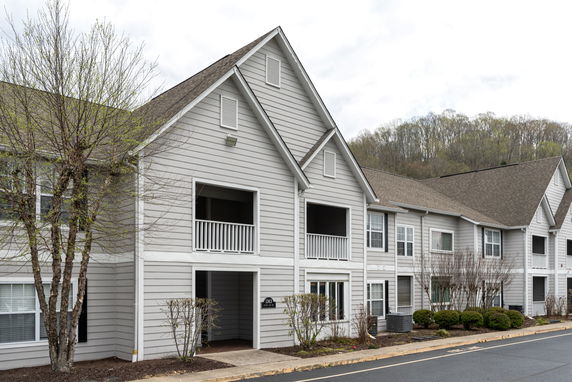 Front view of a two-story residential building with gabled roofs and balconies.
