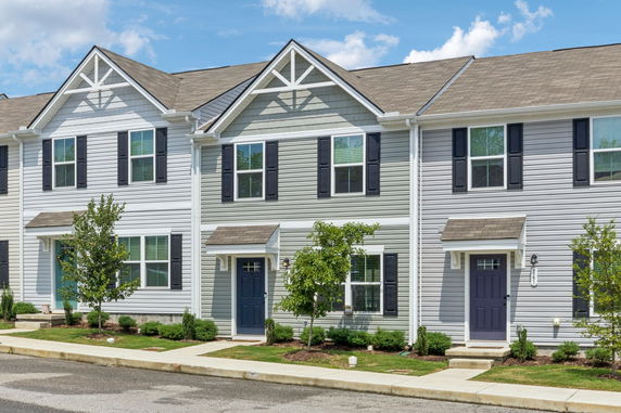Front view of townhouses with gabled roofs and blue doors.