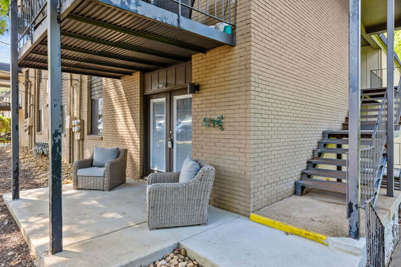 Front view of a multi-story building with beige brick exterior and outdoor seating area.