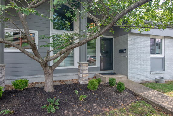 Front view of a house with gray and white exterior and steps leading to the entrance.