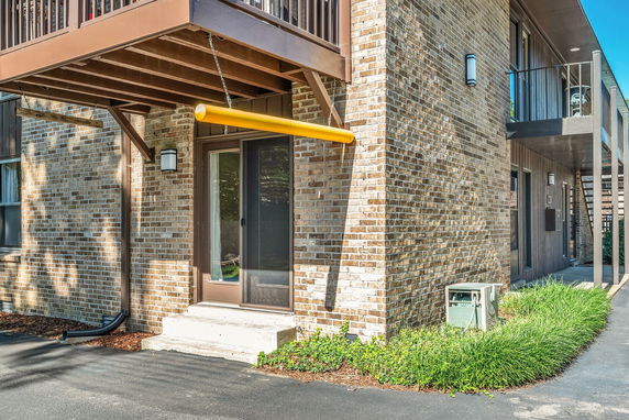Front view of a brick building with a balcony and sliding glass door.