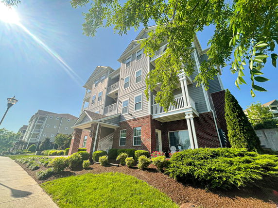 Front view of a multi-story residential building with balconies and brick facade.
