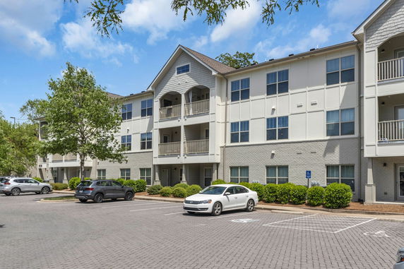 Front view of a multi-story apartment building with balconies and parking area.
