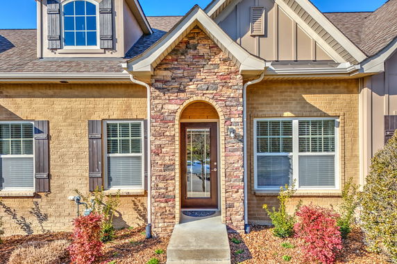 Front view of a house with a central brick entrance and decorative window shutters.