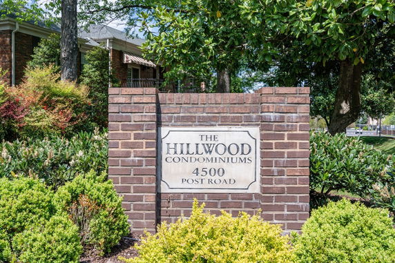 Front view of a building with a brick sign for Hillwood Condominiums.