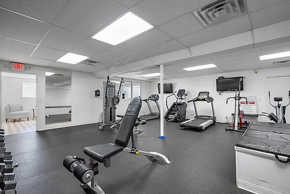 Indoor gym area with exercise equipment including treadmills and weight benches.