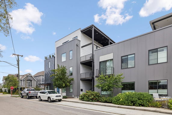 Front view of a modern multi-story building with balconies and large windows.