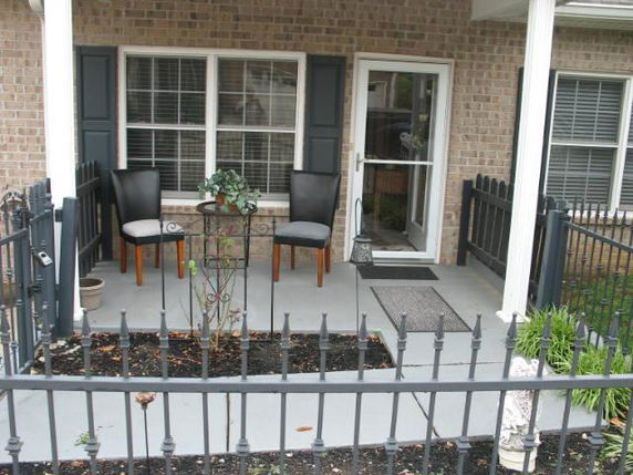 Front view of a house with a small porch area, featuring chairs and a potted plant.