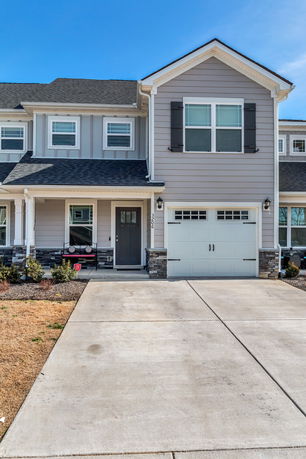 Front view of a two-story house with a garage and covered porch.