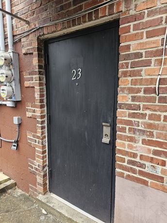 Front view of a door with the number 23 on a brick building.