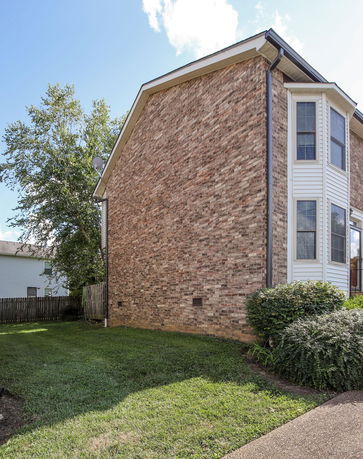 Side view of a two-story brick house with large windows.