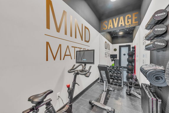 Interior view of a small gym with exercise equipment and motivational wall text.