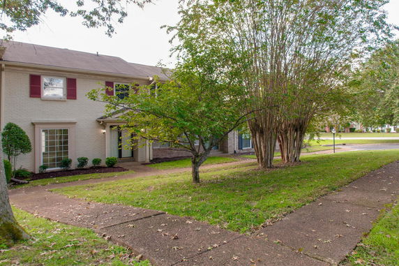 Front view of a two-story house with red shutters and large windows.