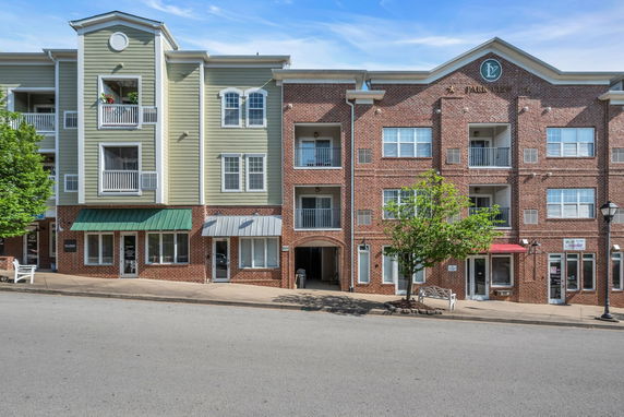 Front view of a multi-story building with brick and siding exterior and multiple balconies.