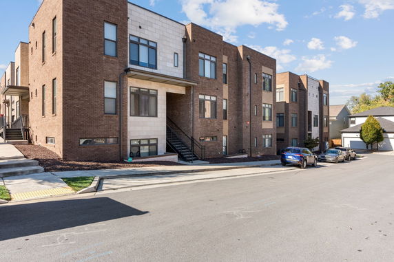 Front view of a modern brick apartment building with multiple windows and an exterior staircase.