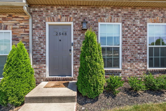 Front view of a brick house entrance with windows and a grey door.