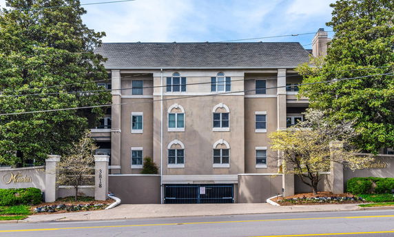 Front view of a multi-story building with gated parking entrance.