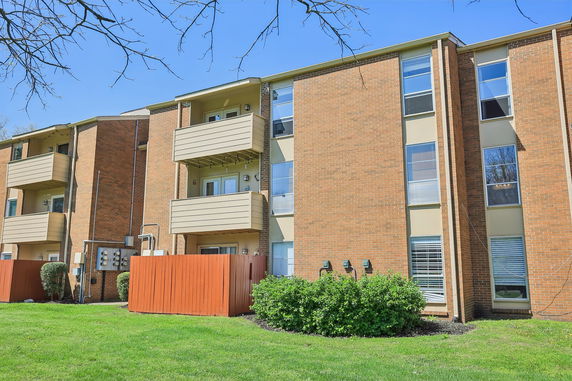 Front view of a multi-story brick apartment building with balconies.