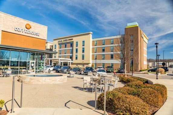 Front view of a hotel building adjacent to a coffeehouse with outdoor seating area.