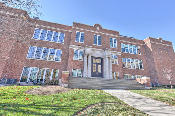 Front view of a multi-story brick building with large windows and a central entrance.
