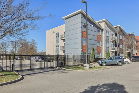 Front view of a multi-story apartment building with a gated parking area.
