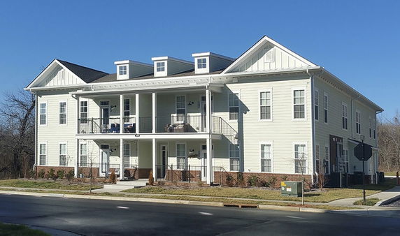 Front view of a two-story building with white siding and a small porch.