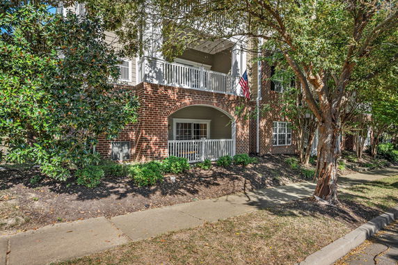 Front view of a brick apartment building with balconies and an American flag.