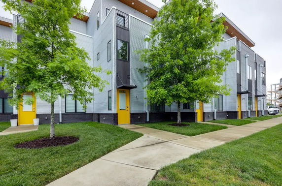 Front view of a modern multi-story building with yellow doors and large windows.