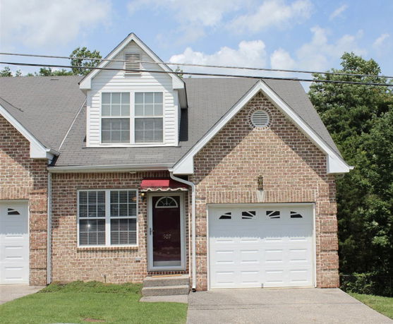 Front view of a brick house with an attached garage and a gabled roof.