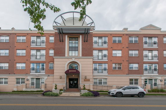 Front view of a multi-story brick building with arched entrance and multiple windows.