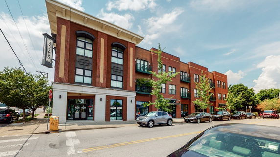 Front view of a three-story building with brick facade and large windows.