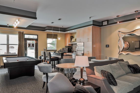 Interior of a club house with a pool table, seating area, and a kitchenette.