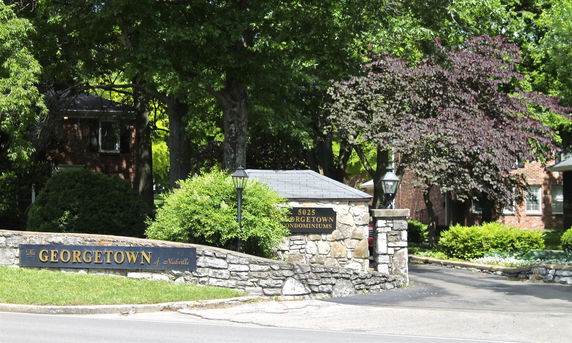 Front view of a residential entrance with a stone wall and decorative lamps.