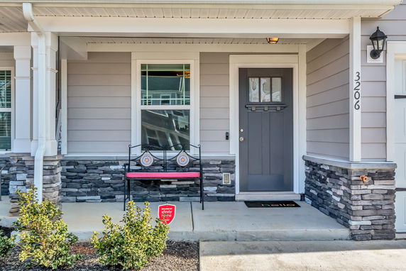 Front view of a house entrance with a bench and stone accents.