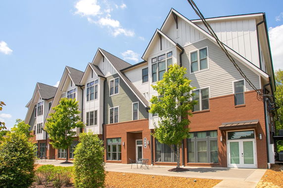 Front view of a multi-story residential building with gabled roofs and brick facade.