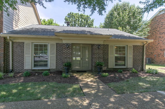 Front view of a single-story house with brick exterior and central entrance.